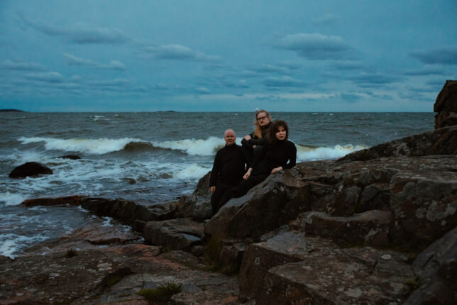 Kuvassa Pauha-orkesteri istuu kalliolla meren rannalla.