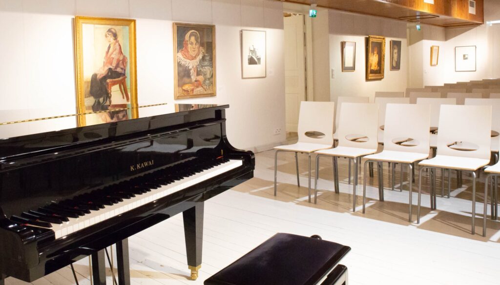 Kuvassa Taidetalon Meeri-sali. Etualalla on flyygeli ja takana penkkirivistöt.